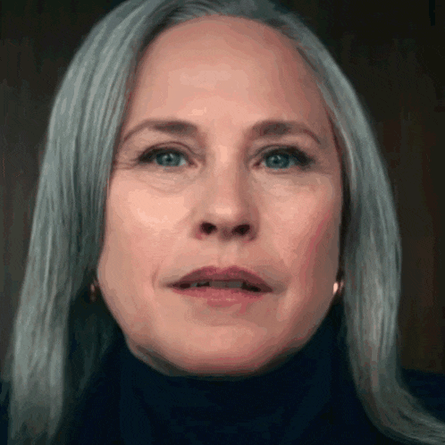 a woman with gray hair and a black turtleneck looks at the camera