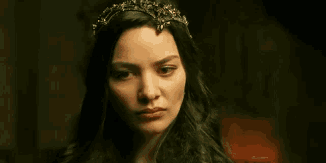 a woman wearing a crown on her head looks at the camera .