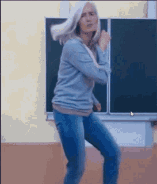 a woman in a classroom is dancing in front of a blackboard .