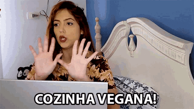 a woman is sitting in front of a laptop with the words cozinha vegana on the screen