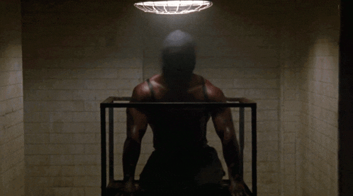 a man is standing in a dark room with a light hanging from the ceiling