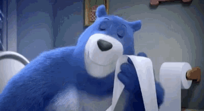 a blue bear is sitting on a toilet holding a roll of toilet paper .