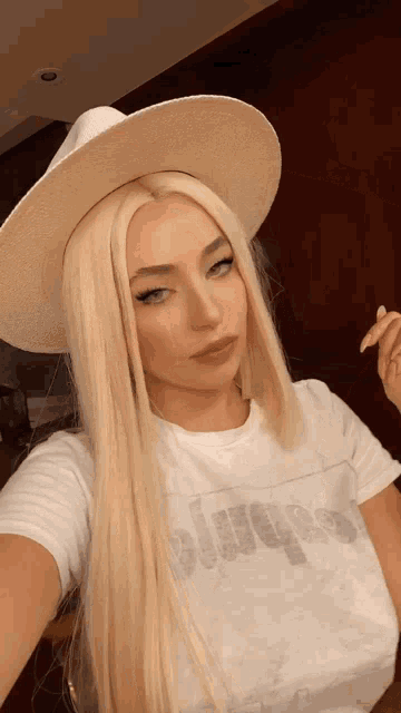 a blonde woman wearing a white hat and a white t-shirt that says always