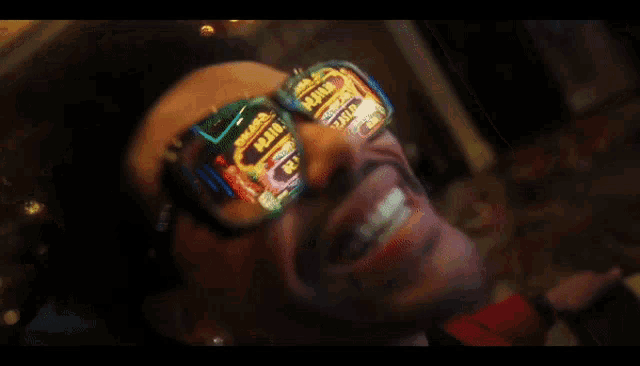 a man wearing sunglasses is smiling in front of a slot machine that says joker