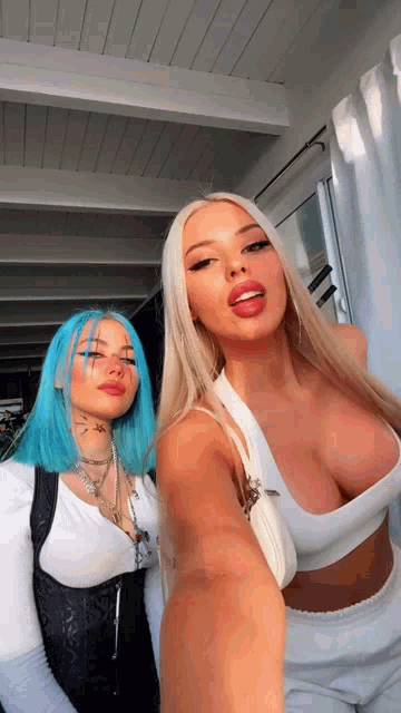 two women with blue hair are taking a selfie together .