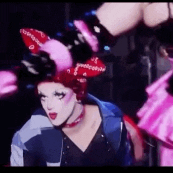 a drag queen wearing bunny ears and a bandana is dancing on a stage .
