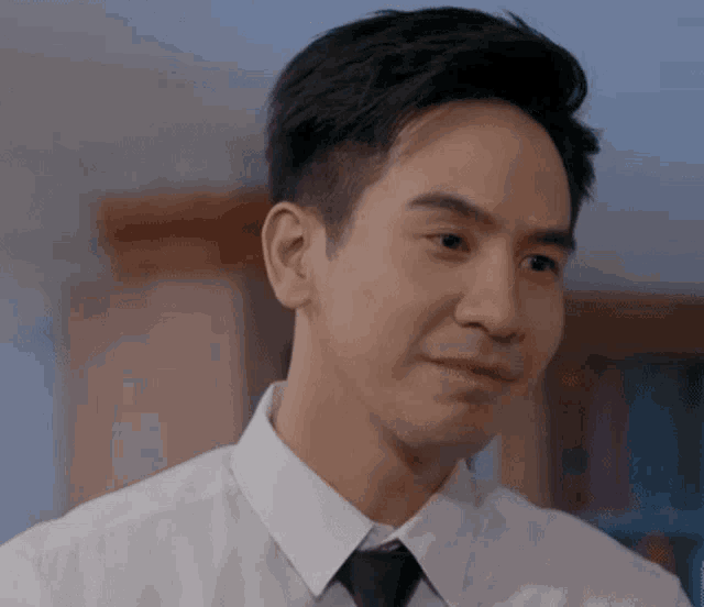 a man in a white shirt and black tie is looking at the camera .
