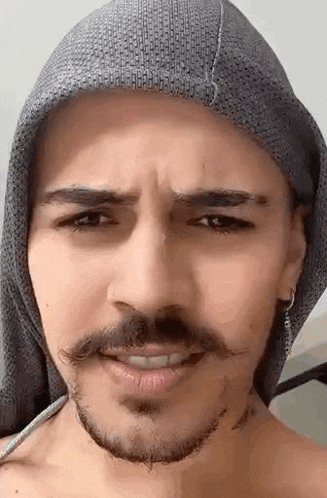 a close up of a man with a beard and mustache wearing a hooded scarf .