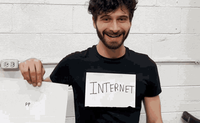 a man in a black shirt holds up a piece of paper that says internet