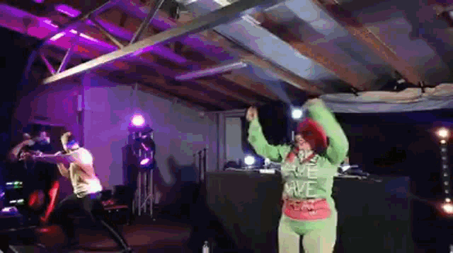 a woman in a green sweatshirt that says " give love " is dancing on stage