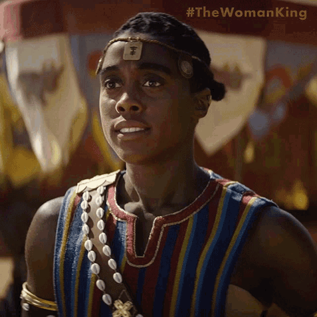 a woman is wearing a striped shirt and a headband with the words #thewomanking written on the bottom