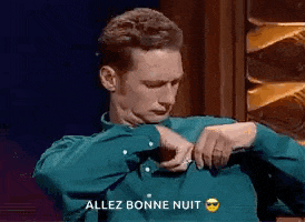 a man in a green shirt is sitting in front of a sign that says allez bonne nuit on it .