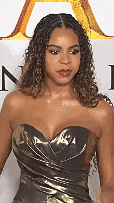 a woman in a strapless dress is standing in front of a wall .