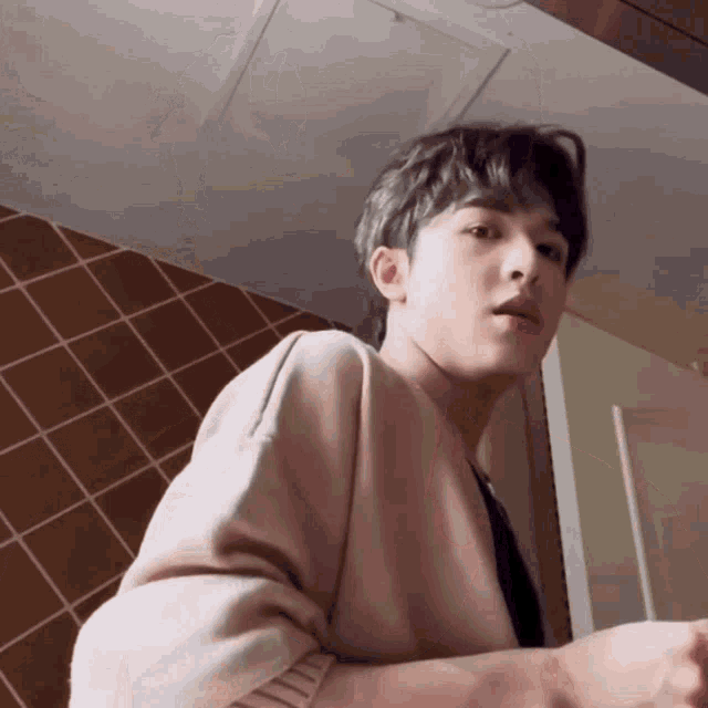 a young man in a pink sweater is looking at the camera