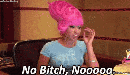 a woman wearing a pink wig and a blue shirt is sitting at a desk and says no bitch nooooo .
