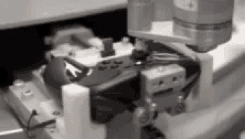 a black and white photo of a robotic arm holding a piece of equipment .