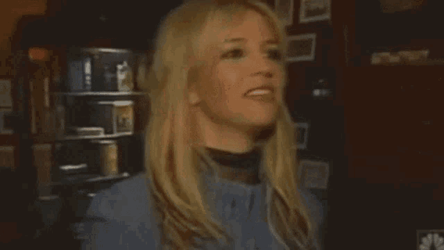 a woman is laughing in a dark room with a microphone in her hand .