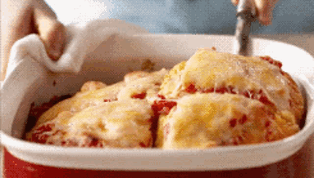 a person is taking a piece of pizza out of a casserole dish with a fork