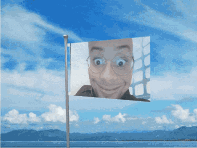 a flag with a man 's face on it flies in the wind