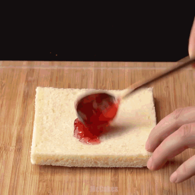 someone is spreading jam on a piece of bread