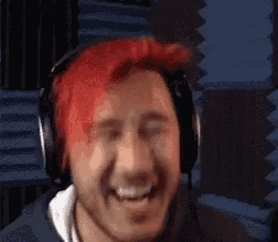 a man with red hair wearing headphones is smiling and making a funny face .
