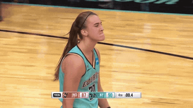 a female basketball player wearing a number 20 jersey stands on the court