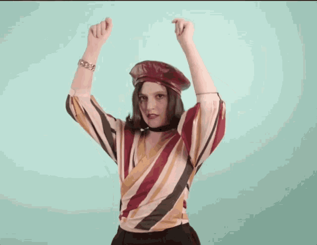 a woman wearing a red beret and a striped shirt is dancing