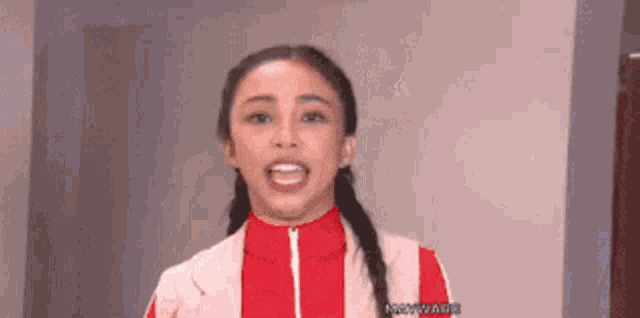 a woman in a red jacket is making a funny face and smiling .