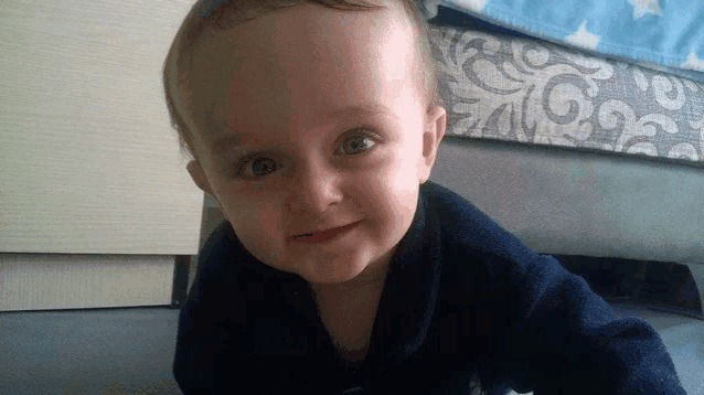 a baby in a blue sweater is smiling for the camera