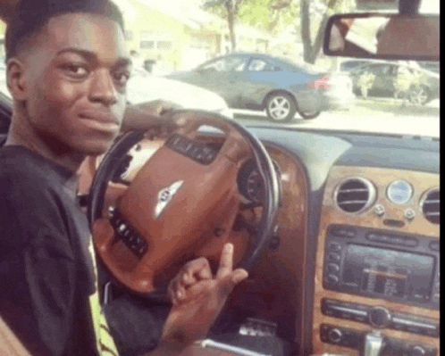 a man is sitting in a bentley car and giving the middle finger