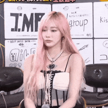 a woman with pink hair is sitting in front of a sign that says j.m.f group