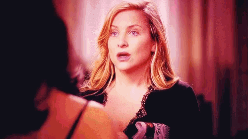 a woman is talking to another woman in a room while looking at herself in a mirror .