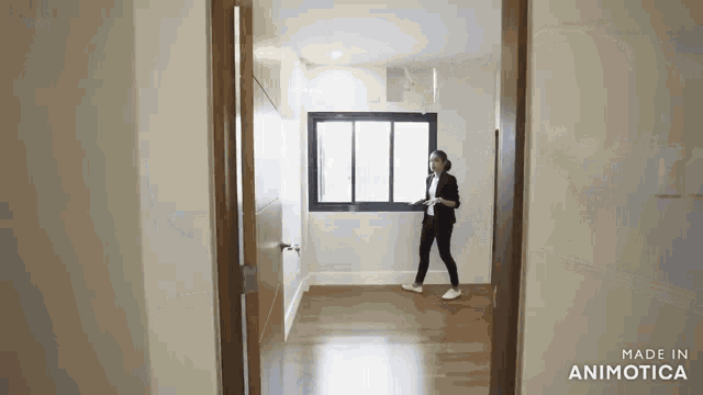 a woman is standing in an empty room next to a window holding a tablet .