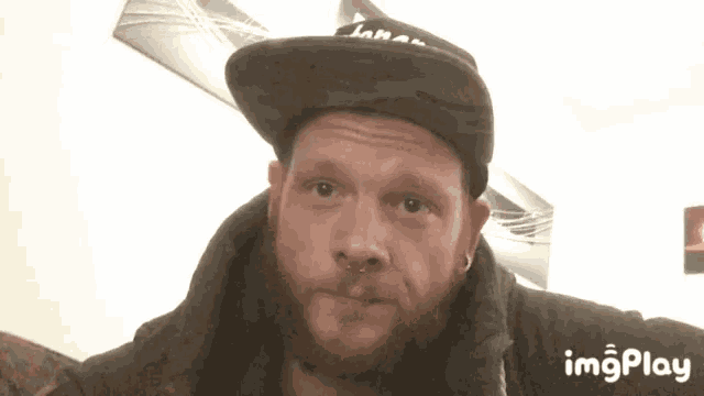 a man with a beard is wearing a hat with the word imgplay on the bottom right