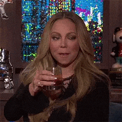 mariah carey is holding a glass of wine in her hand .