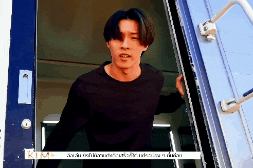 a man in a black shirt is standing in a doorway with a sign that says kim on it