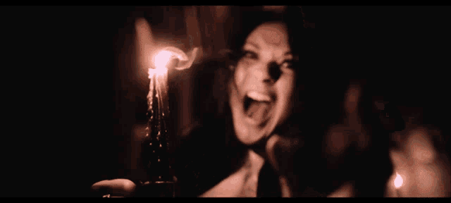 a close up of a woman 's face with a candle in the background and a caption that says ' screaming '