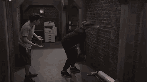 a man and a woman are standing next to each other in a room with a brick wall .