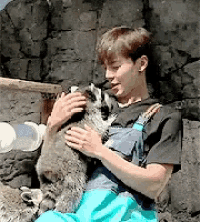 a man in overalls is holding a raccoon in his arms