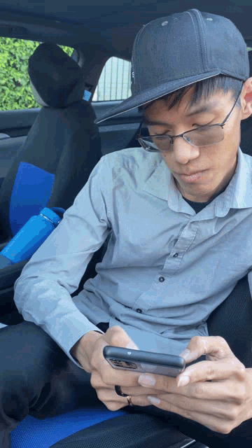 a man wearing a hat and glasses is looking at his cell phone