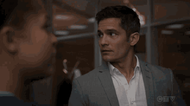 a man in a suit and white shirt is talking to another man in a ctv show