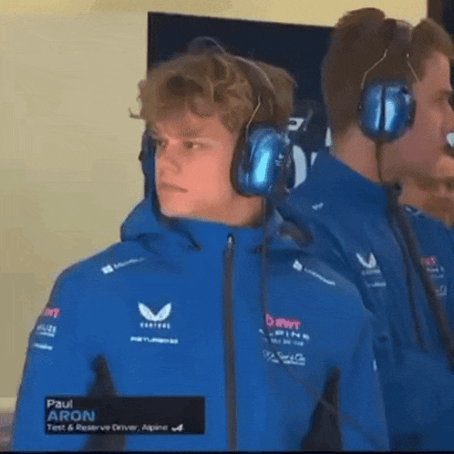 a man wearing a blue jacket and headphones is standing next to another man wearing headphones .