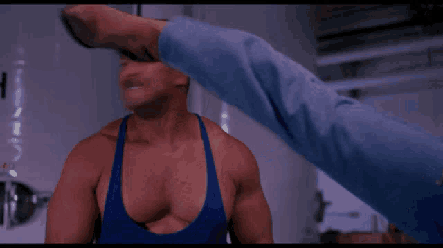 a man in a blue tank top is kicked in the face by another man