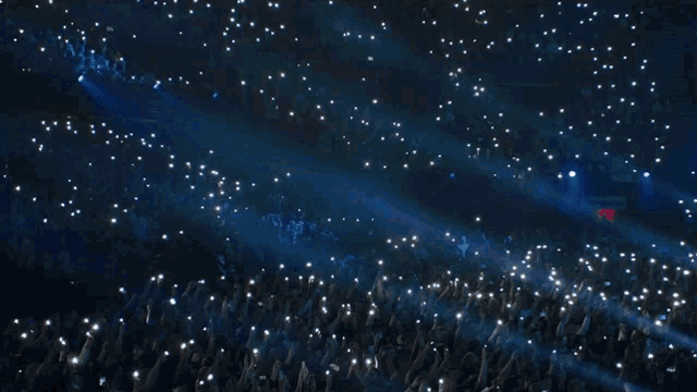 a crowd of people holding up their cell phones at a concert with a sign that says stadium