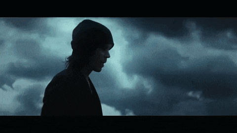 a silhouette of a person standing in front of a cloudy sky .