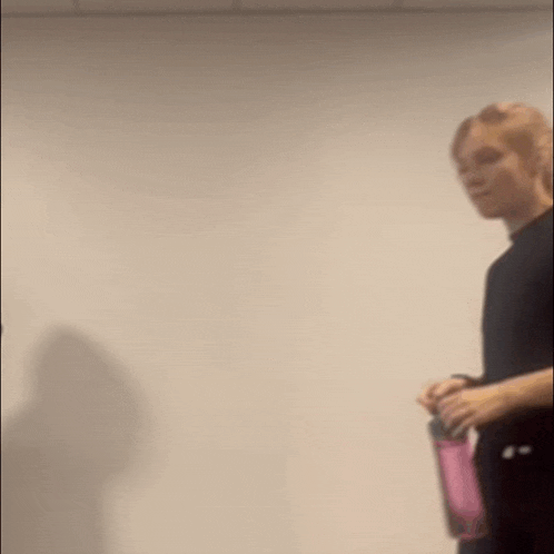 a man in a black shirt is holding a pink water bottle .