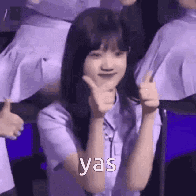 a woman in a purple shirt is giving a thumbs up sign .