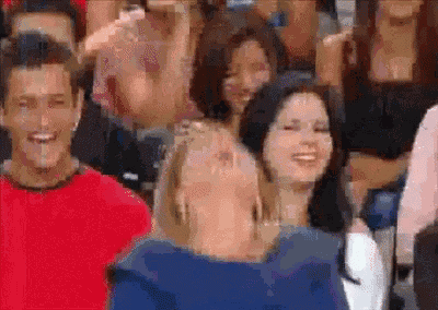 a group of people are sitting in a stadium watching a game and one woman is smiling .