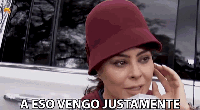 a woman wearing a burgundy hat says a eso vengo justamente