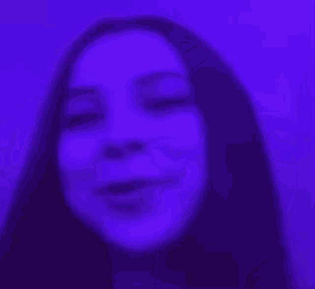 a close up of a woman 's face with a purple light behind her .